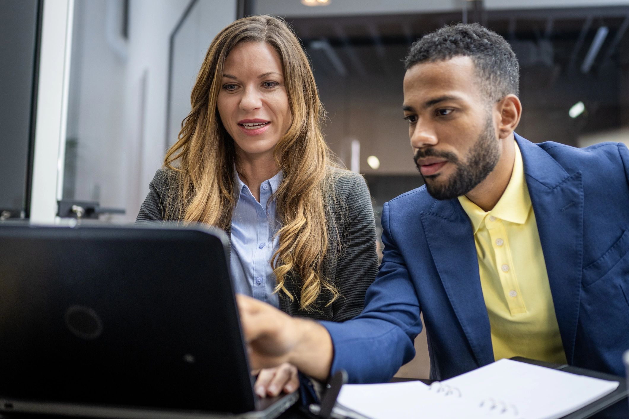Two professionals collaborating on a laptop in a meeting room